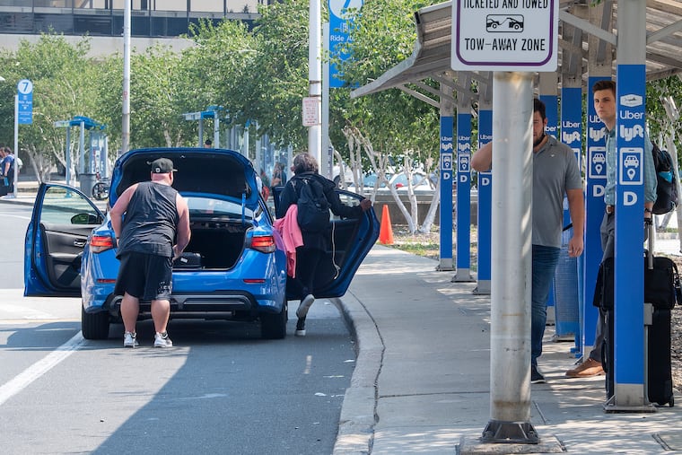 Uber and Lyft drivers picking up arriving passengers outside the baggage claim in July 2021 at the Philadelphia International Airport.