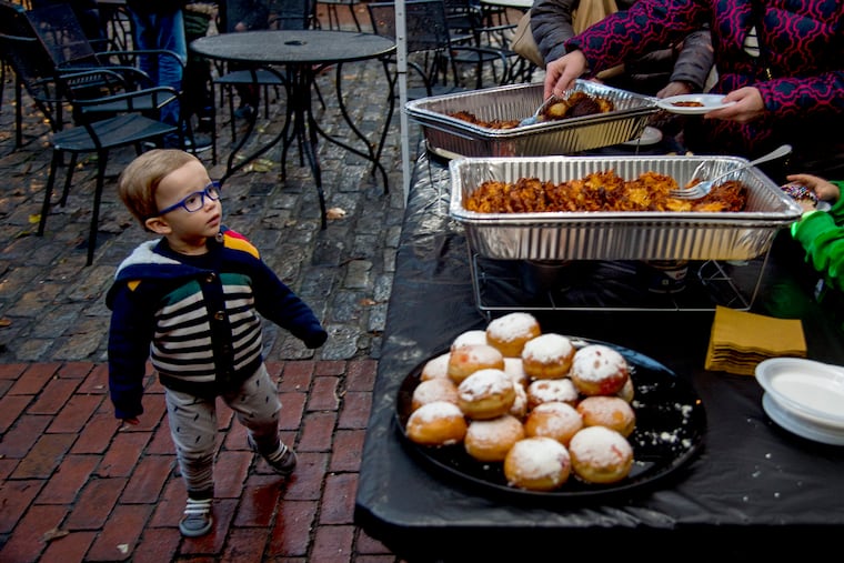 Two and 1/2-year-old Aaron Hinrichs checks out the table of free beverages and traditional foods like latkes and donuts in the courtyard of the Betsy Ross House on Dec. 2, 2018, before the lighting there of a community menorah for the first night of Hanukah.