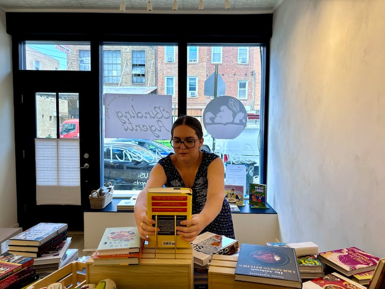 Catie Gainor  sets up displays cookbooks in her upcoming store.