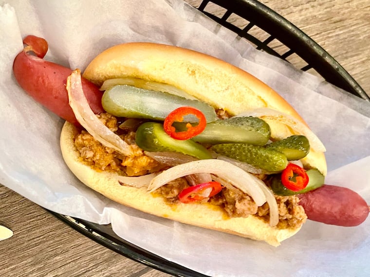 A hot dog is topped with Khmer prohok made from ground boar at Mawn for a Southeast Asian spin on a chili dog.