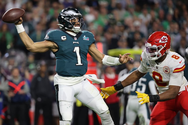 Eagles quarterback Jalen Hurts is pressured by Kansas City Chiefs defensive end Carlos Dunlap during the fourth quarter in Super Bowl LVII.