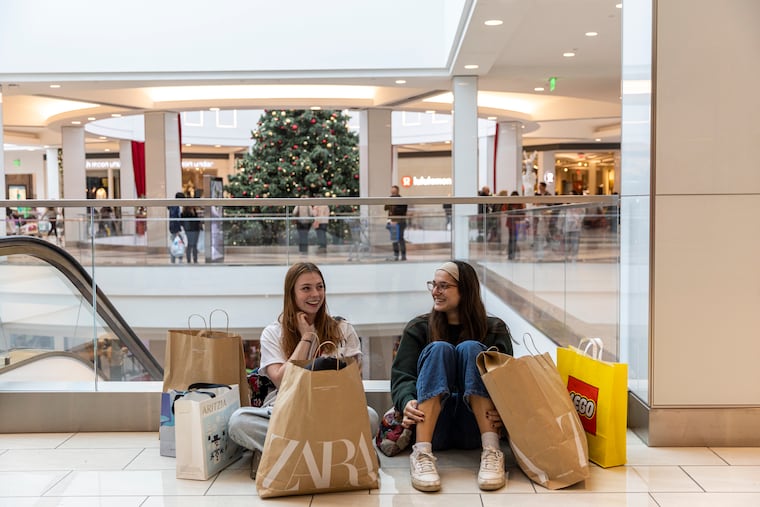 Two shoppers sitting with their bags of bought items during Black Friday at the King of Prussia Mall on Friday, Nov. 25, 2022.